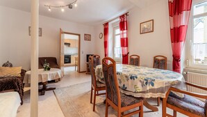 A dining area with a table set for four, wooden chairs, and a view of the kitchen through an open door. - Ferienwohnung in Ediger (Ediger-Eller)