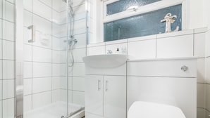 A modern bathroom with a glass shower enclosure, a white sink, and a toilet. - Platform Avenues Area Apartments (Hull)