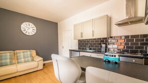 A modern kitchen with a black tiled backsplash, white cabinets, and a toy van on the counter. - Platform Avenues Area Apartments (Hull)