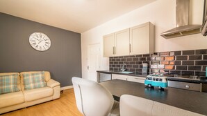 A modern kitchen with a black tiled backsplash, white cabinets, and a toy van on the counter. - Platform Avenues Area Apartments (Hull)