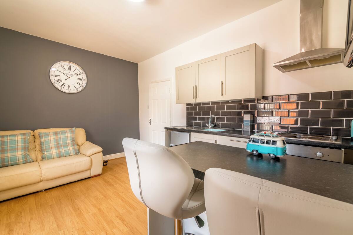 A modern kitchen with a black tiled backsplash, white cabinets, and a toy van on the counter.