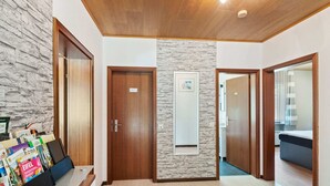 Eine Hotelhalle mit Steinwand, Holztüren und einer Rezeption mit Zeitschriften.