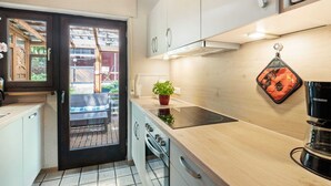 Eine moderne Küche mit Holzbalkendecke, einem schwarzen Kochfeld und einer Kaffeemaschine.