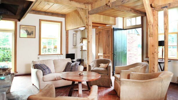 A rustic wooden interior with a sofa, armchairs, and a round table. - Cozy Apartment in Enschede near Forest (Enschede)