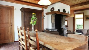 A wooden dining table with chairs, a fireplace, and a brick floor. - Cozy Apartment in Enschede near Forest (Enschede)
