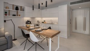 A modern kitchen with white cabinets, a wooden dining table, and black chairs. - Acropolis Golden Suites | 2nd Floor (Athina)