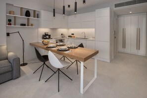 Een moderne keuken met witte kasten, een houten eettafel en zwarte stoelen.
