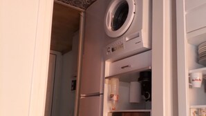Une cuisine compacte équipée d’un lave-linge et d’un sèche-linge intégrés, d’un four à micro-ondes et d’une cuisinière.