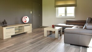 Una sala de estar moderna con un sofá, una mesa de centro, un mueble para televisión y un ventanal grande.