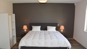 Un dormitorio moderno con una cama grande, dos mesitas de noche con lámparas, un armario y una lámpara de techo original.