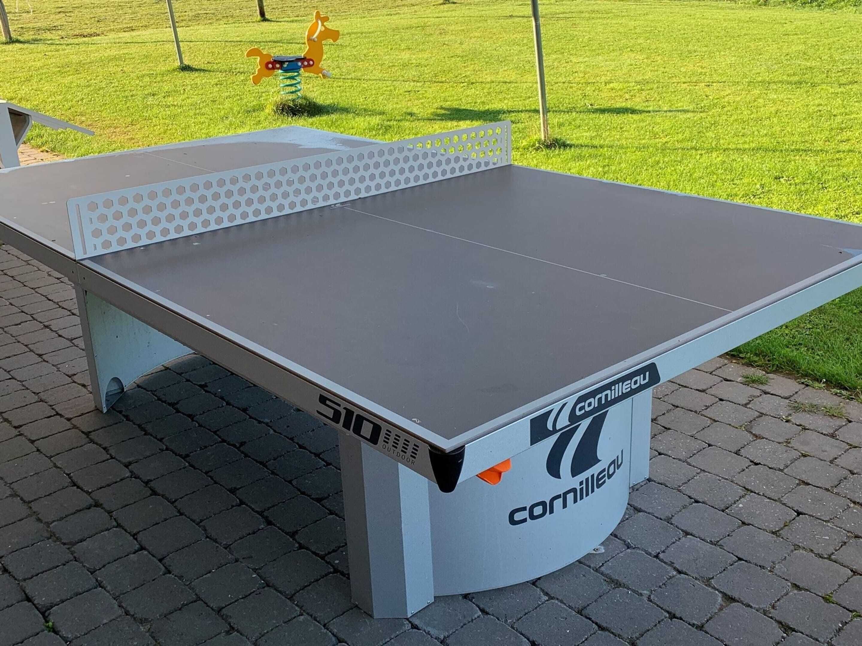 A table tennis table with the brand 'Cornilleau' and model 'S10' outdoors.