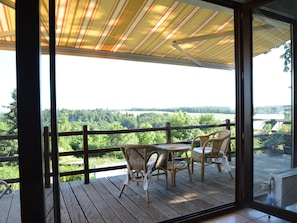 A wooden deck with wicker furniture and a view of a green landscape. - Spacious House With Beautiful Terrace (Hastiere)