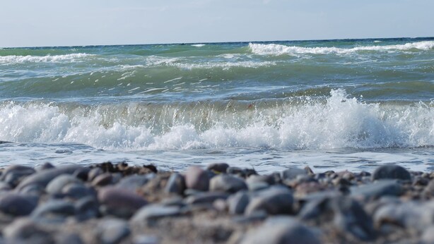 Uma costa rochosa com ondas quebrando na praia.