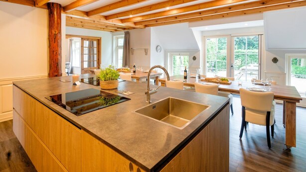 A modern kitchen with a central island, wooden beams, and large windows. - Spacious Farmhouse With Sauna, Hottub (Noardburgum)