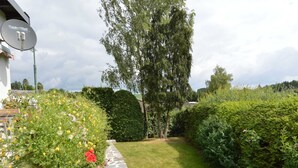 A garden pathway with a stone border, surrounded by lush greenery and flowering plants. - Cozy Holiday Home in Boevange-clervaux With Garden (Wincrange)