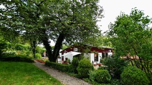 A house with a red roof, surrounded by lush greenery and a gravel path. - Luxury Holiday Home in the South of Limburg Province with Hot Tub, Sauna, Large Garden (Walem)
