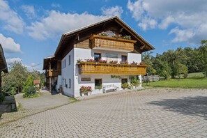 A two-story building with a balcony, a wooden facade, and a paved courtyard.