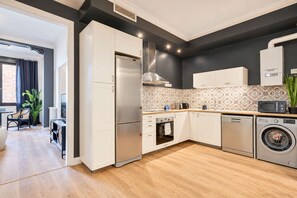 A modern kitchen with a stainless steel refrigerator, oven, microwave, and dishwasher. - Sweett | Sepulveda XI (Barcelona)