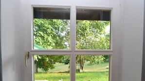 A room with a white door and a window with a view of a grassy yard and trees. - Tranquil Garden Apartment (Regen)