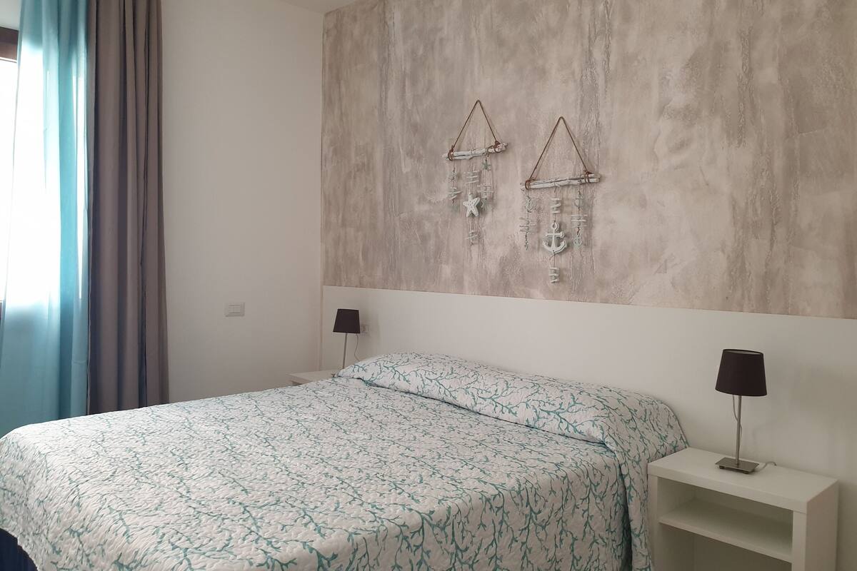 A bedroom with a bed, two bedside lamps, a nightstand, and a wall-mounted decoration.