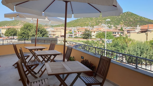 A balcony with outdoor seating, including tables and chairs, and umbrellas. - Caletta sul Mare (Siniscola)