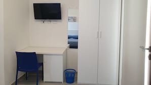 A room with a desk, a chair, a television, a wardrobe, and a small basket. - Caletta sul Mare (Siniscola)