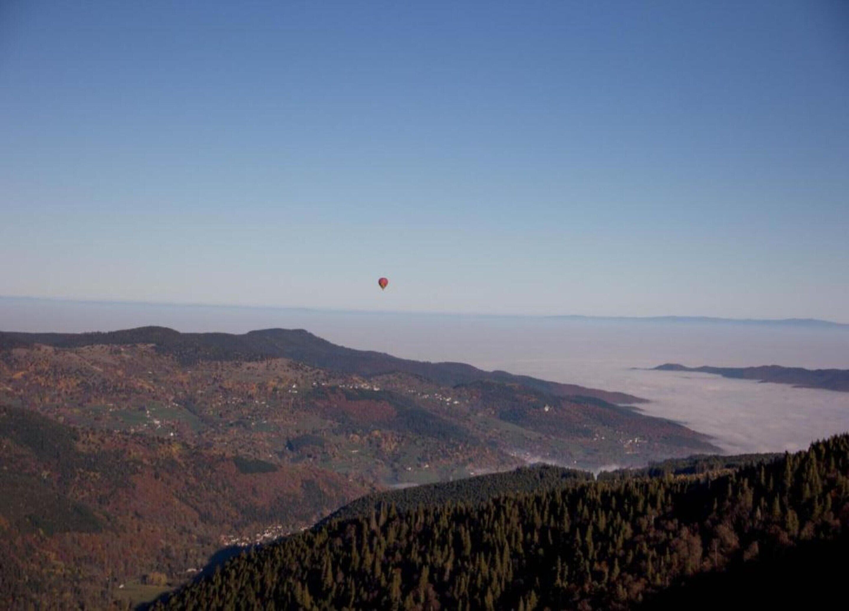 Een panoramisch uitzicht op een berglandschap met een rode ballon in de lucht.