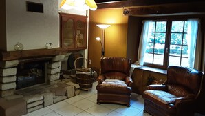 Una sala de estar acogedora con chimenea, sillones de cuero, un ventanal con vistas y una lámpara colgante.