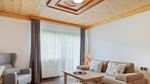 A living room with a sofa, armchair, wooden coffee table, and a lamp. - Cosy Apartment in Muhlbach With Balcony (Bramberg am Wildkogel)
