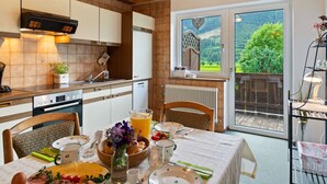 A cozy kitchen with wooden cabinets, a built-in oven, and a window overlooking a lush garden. - Cosy Apartment in Muhlbach With Balcony (Bramberg am Wildkogel)