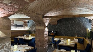 A restaurant with stone walls, wooden tables, and blue chairs. - Penzion Pohoda (Trutnov)