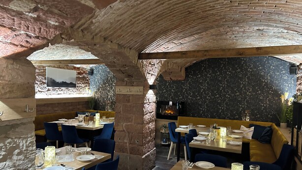 Un restaurante con paredes de piedra, mesas de madera y sillas azules.