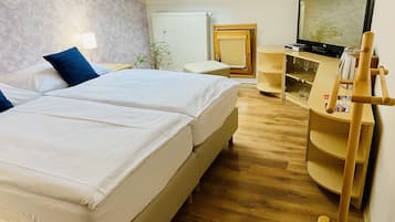 Una habitación de hotel con dos camas, televisión, aparador de madera y tragaluz.