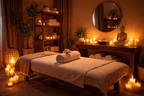 A spa room with two beds, candles, a Buddha statue, and a mirror.