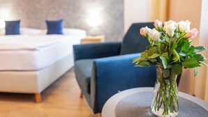 A hotel room with a bed, a chair, a vase with flowers, and a bedside table. - Penzion Pohoda (Trutnov)