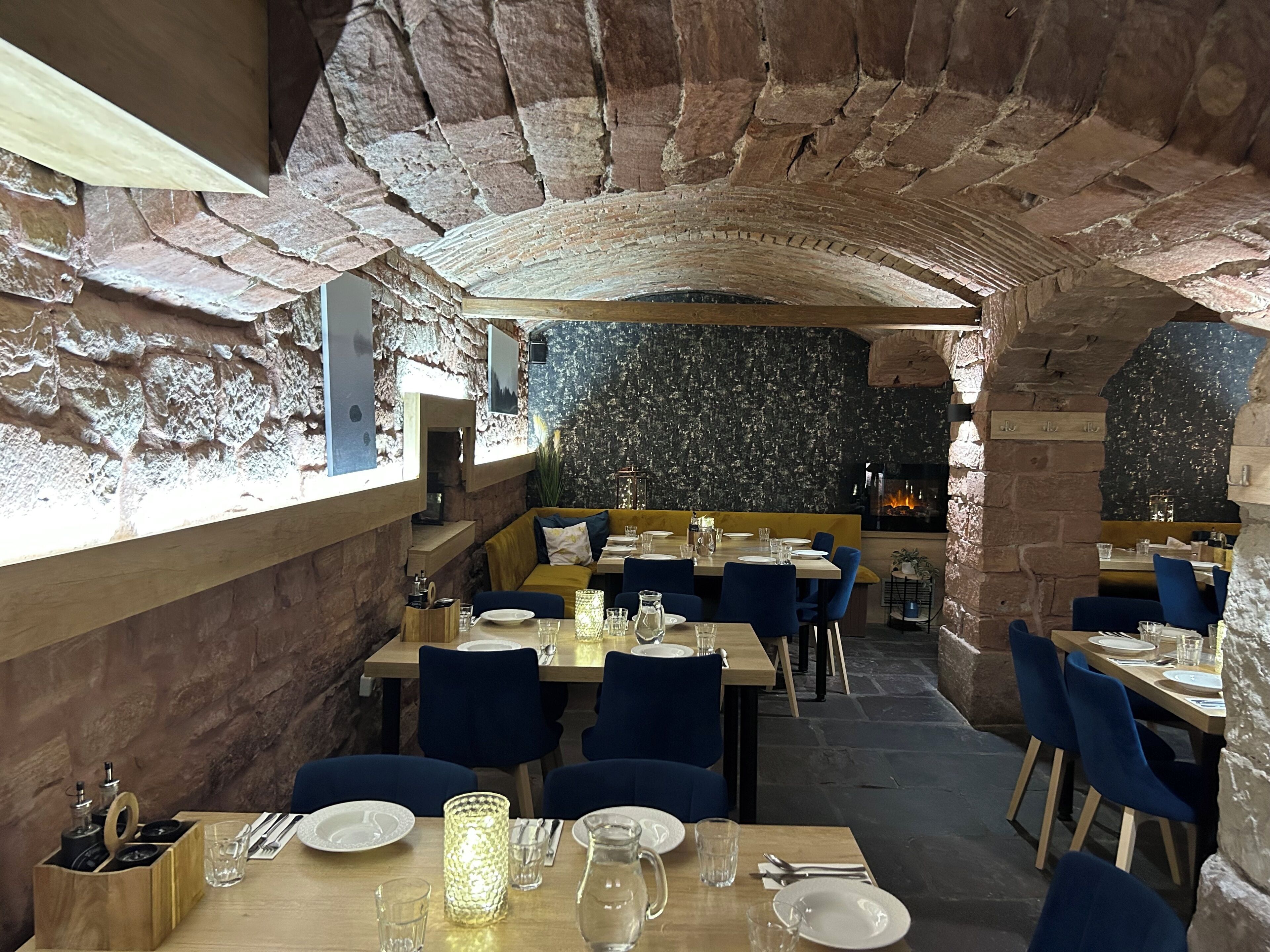 Un restaurante con paredes de piedra, mesas de madera y sillas azules.