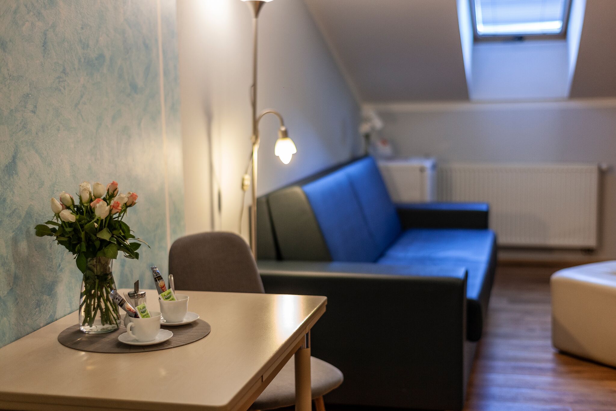 Une pièce moderne avec une table, un vase de fleurs et un canapé bleu.