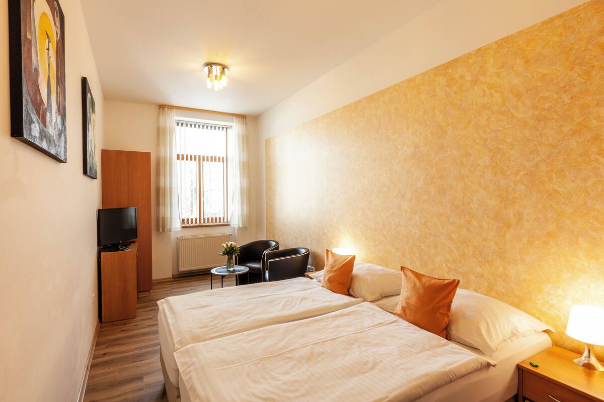 A hotel room with two beds, a TV, a desk, and a chair.