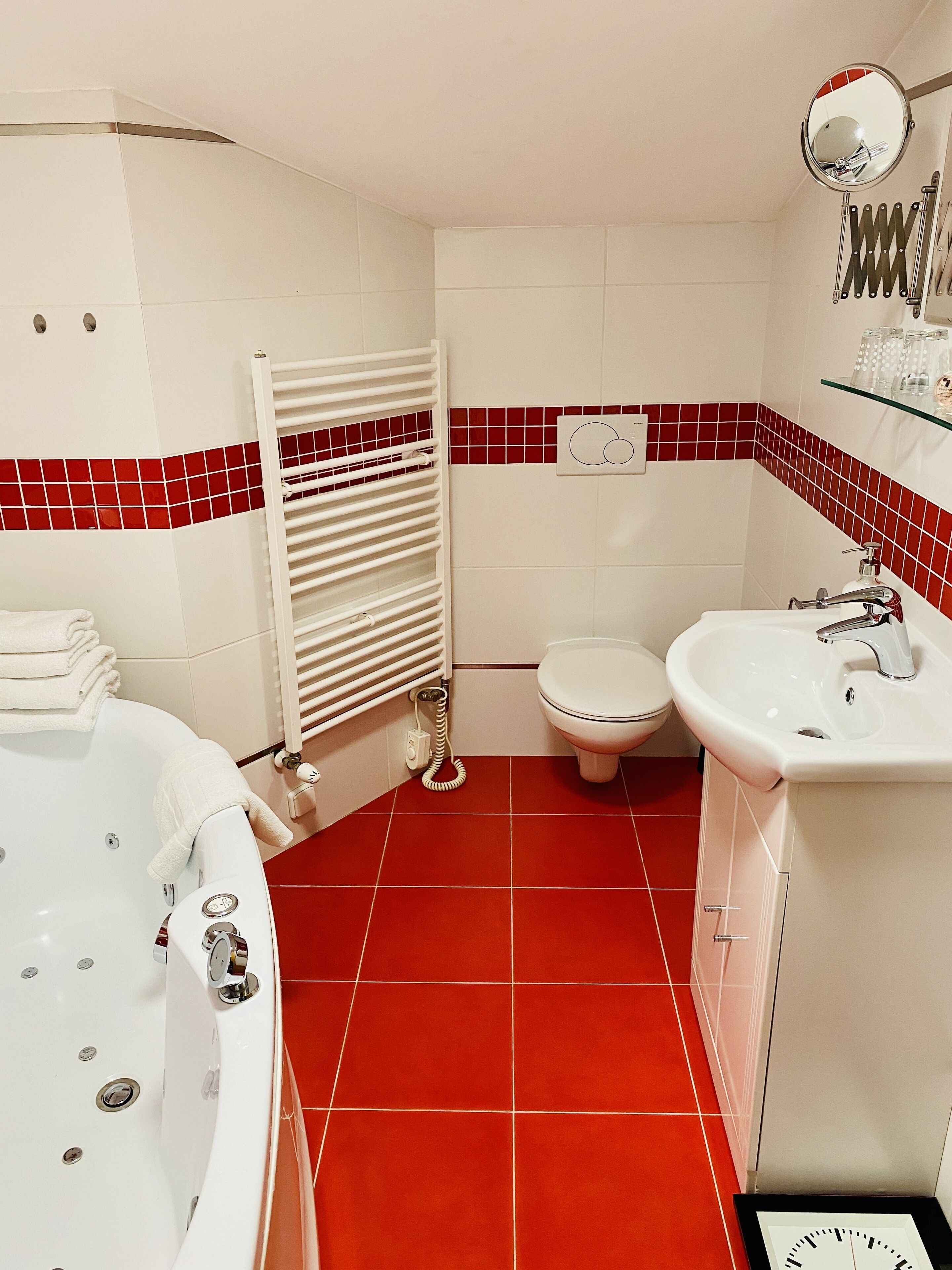 Ein Badezimmer mit einer weißen Badewanne, einem weißen Waschbecken und einer Toilette. An der Wand befinden sich ein Handtuchhalter und ein Spiegel.