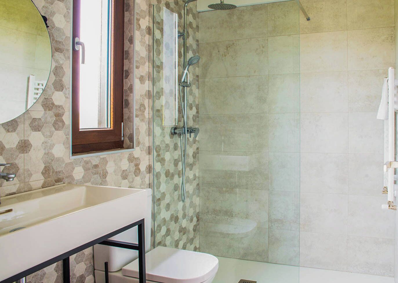 A bathroom with a glass-enclosed shower, a white sink, and a toilet.