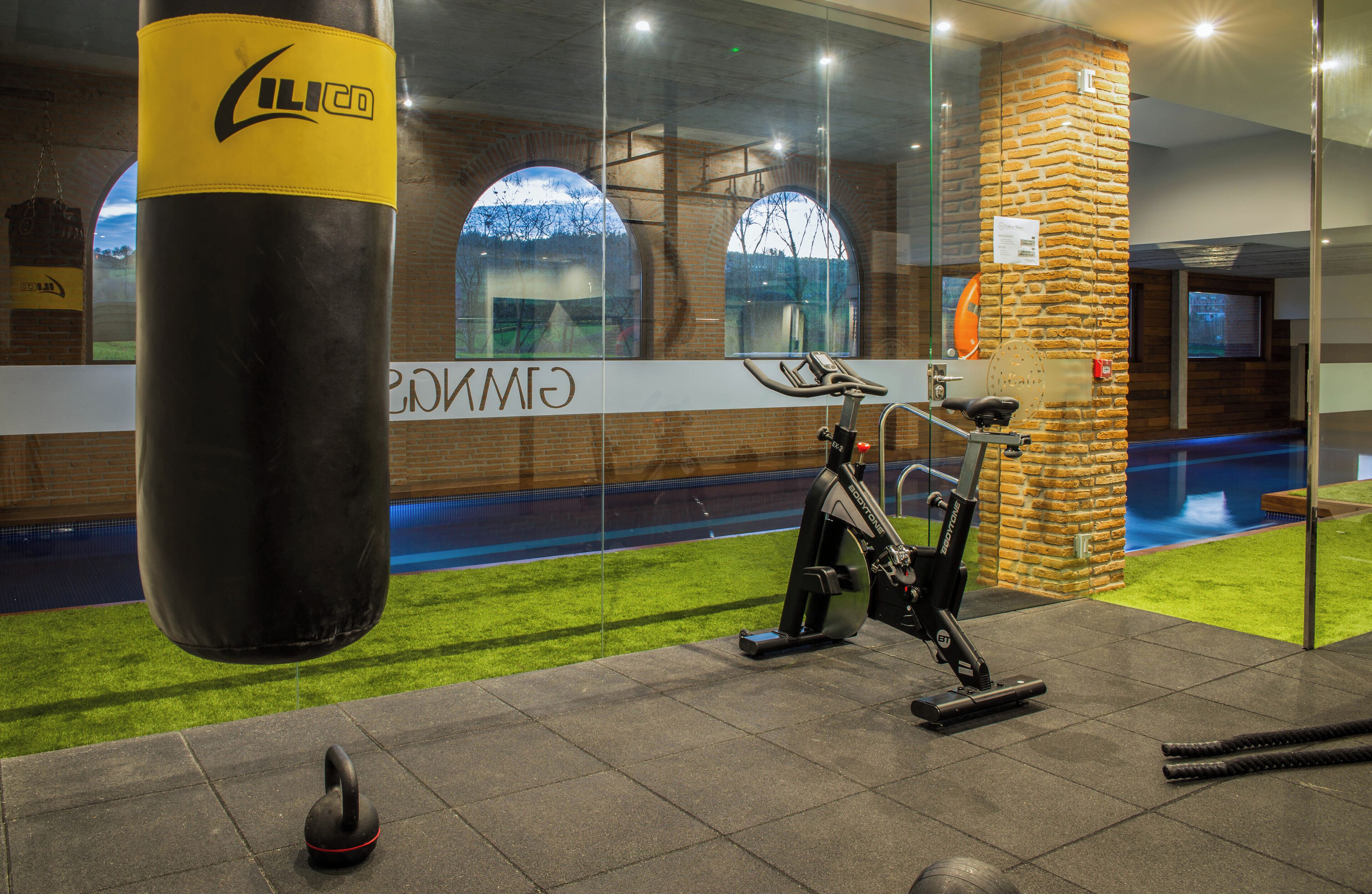 Un gimnasio con un saco de boxeo, bicicletas estáticas y un pilar de ladrillo.