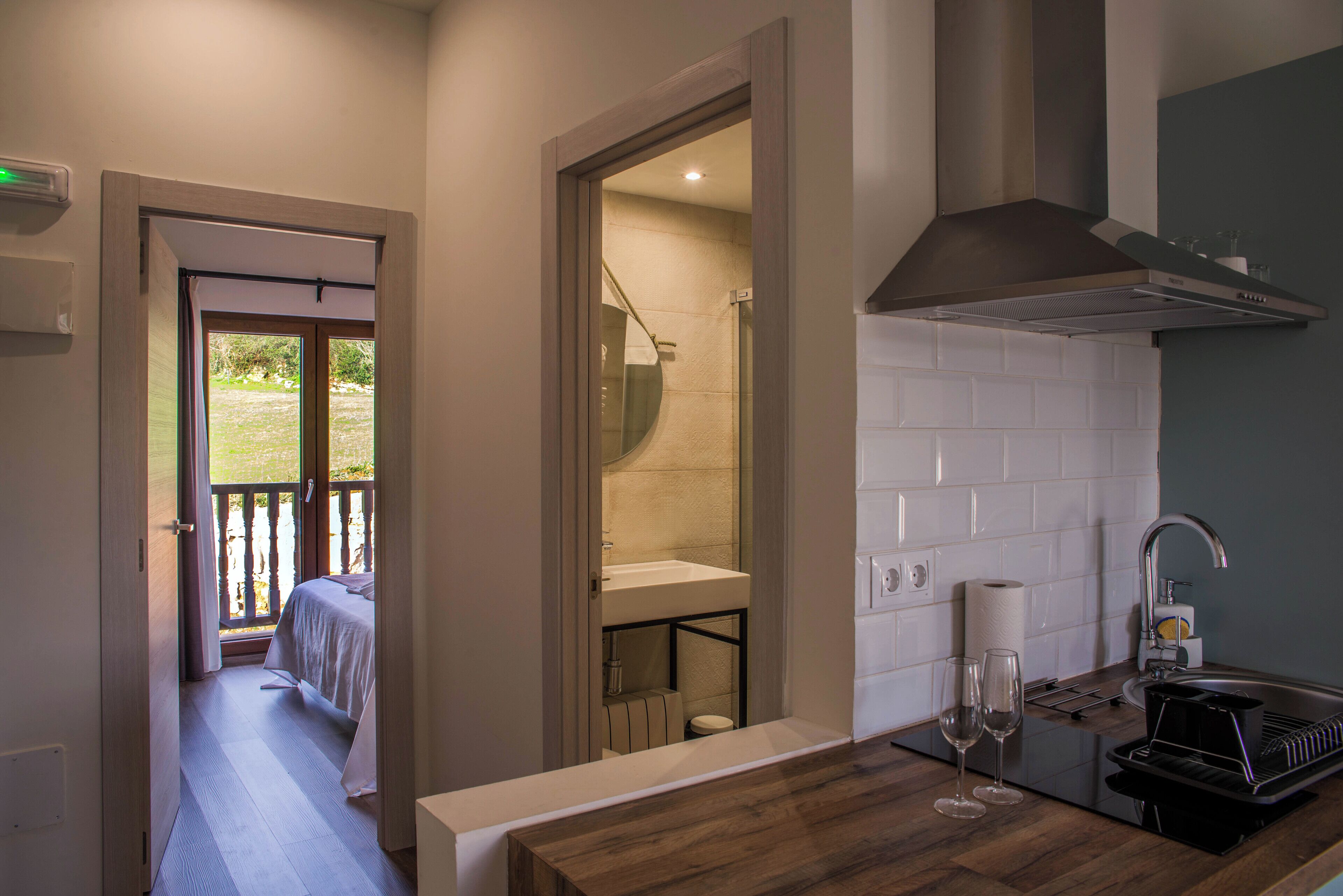 Una habitación de hotel pequeña con balcón, kitchenette y baño.