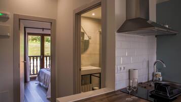 Una habitación de hotel pequeña con balcón, kitchenette y baño.