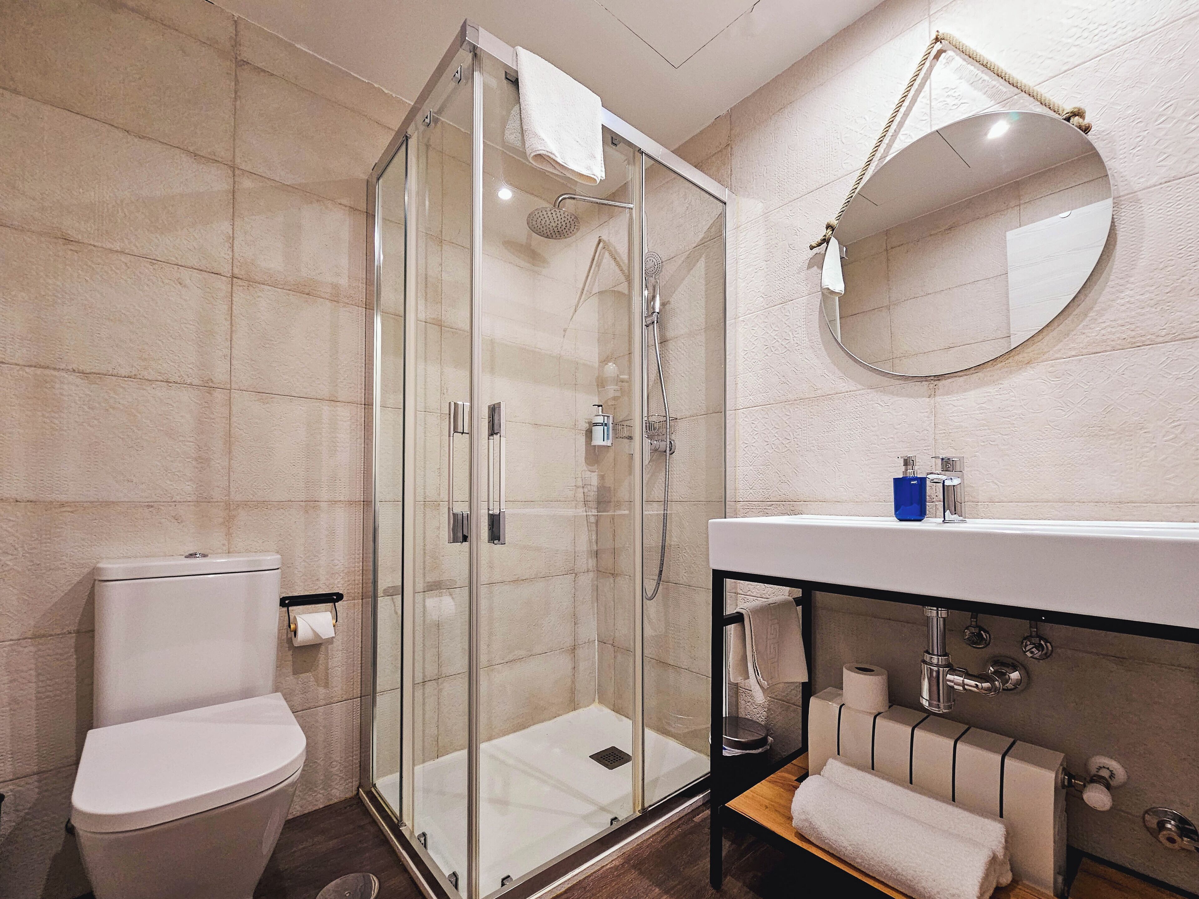 A modern bathroom with a glass-enclosed shower, a white toilet, a sink with a mirror, and a towel rack.