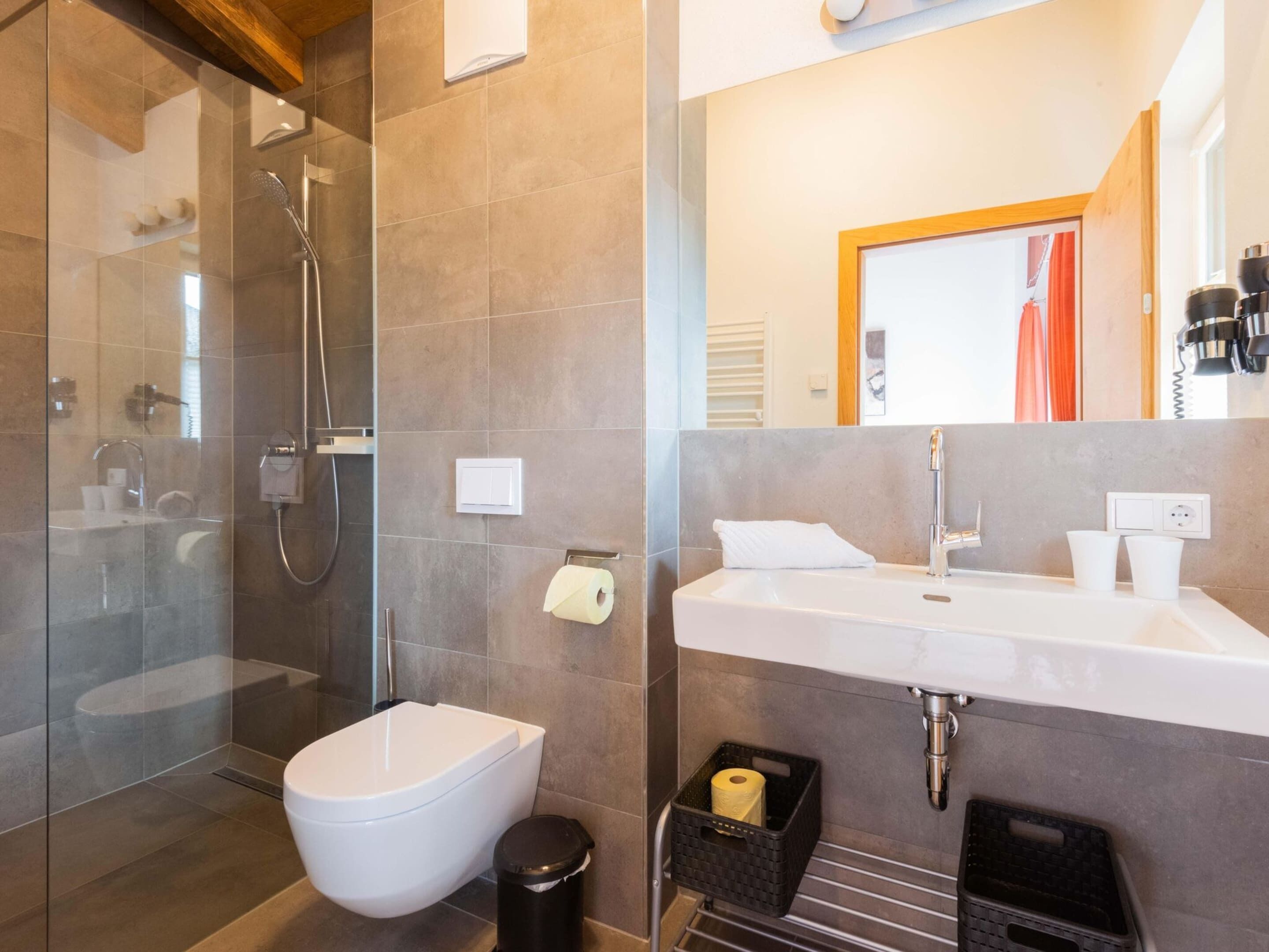 Une salle de bain moderne avec une douche à parois de verre, des toilettes blanches, un lavabo avec un miroir et un porte-serviettes.