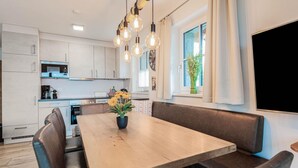 Una cucina moderna con mobili bianchi, un tavolo da pranzo in legno con panche e un lampadario.