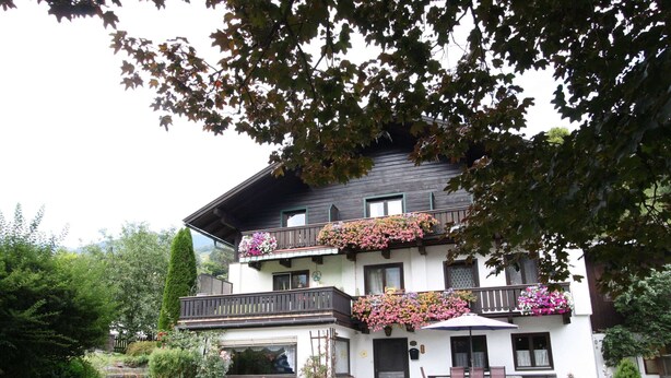 A two-story building with a balcony, a small garden, and a paved driveway. - Apartment in Niedernsill Near Zell am See Ski Area (Niedernsill)