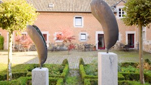 Two abstract sculptures in a courtyard with a brick building in the background. - Pleasing Holiday Home in Richelle With Garden, Terrace, BBQ (Vise)