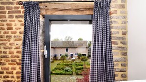 A room with a bed, a window with curtains, and a view of a brick building and garden. - Pleasing Holiday Home in Richelle With Garden, Terrace, BBQ (Vise)