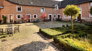 A courtyard with a brick building, stone paving, and a small tree. - Pleasing Holiday Home in Richelle With Garden, Terrace, BBQ (Vise)